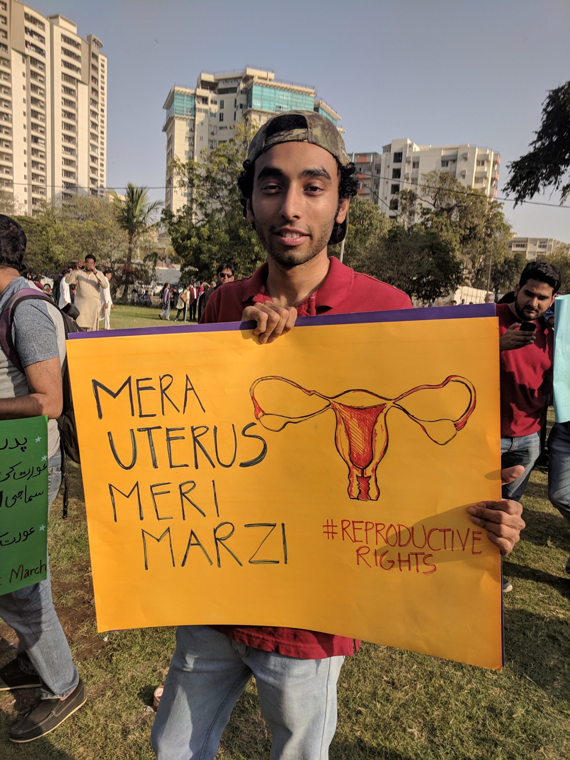 A guy holding an orange sign which reads "Mera Uterus Meri Marzi"